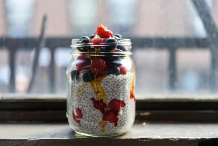 a glass jar filled with chia pudding, layered with berries and a drizzle of honey. a glass jar filled with chia pudding, layered with berries and a drizzle of honey.