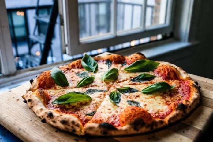 A high-resolution, slightly vintage-filtered image of a classic Margherita pizza resting on a wooden cutting board.