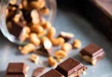 Peanut Toffee Chocolate Clusters You’ll Hide from Your Own Family close-up of broken shards of peanut toffee chocolate on a slightly scratched metal baking sheet.