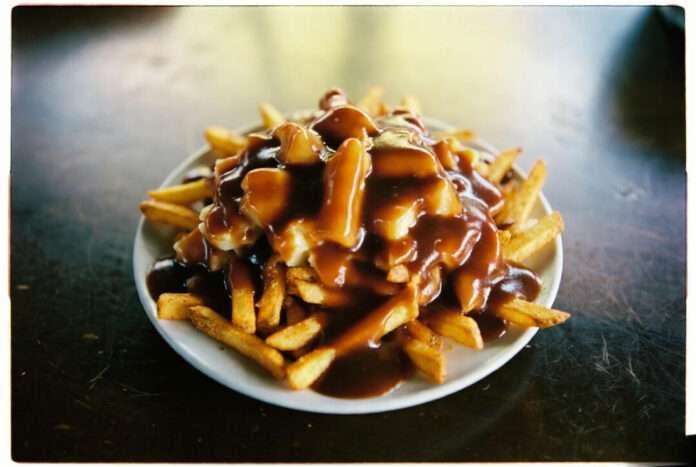 a messy plate of poutine on a scratched diner table. a messy plate of poutine on a scratched diner table.