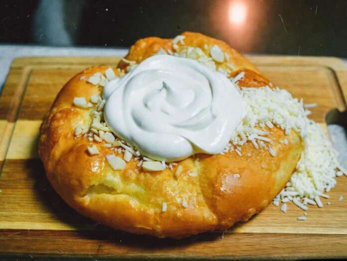 puffy golden langos sitting on a wooden cutting board. puffy golden langos sitting on a wooden cutting board.