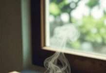 Dudhi Kofta Curry a steaming bowl of Dudhi Kofta Curry placed on a worn wooden table near a window.